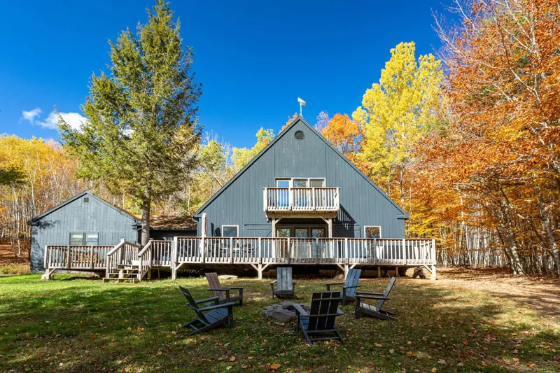Cottage exterior with multi-level decks, fire pit, Adirondack chairs, and fall foliage