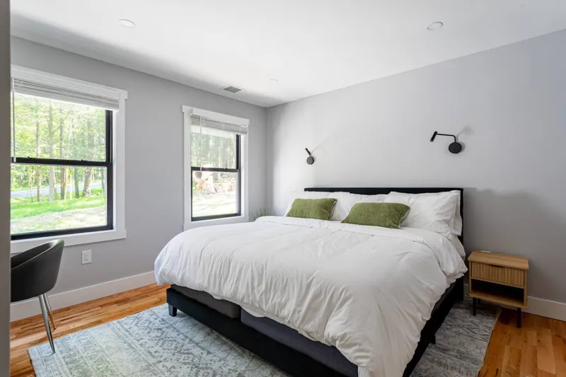 Modern Retreat: Enjoy serene views from this stylish bedroom with plush bedding and natural light!