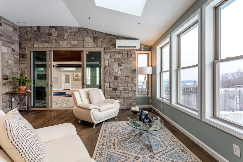 Sunroom sitting area with stone accent wall, armchairs, and coffee table