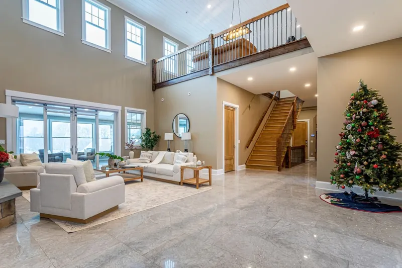 Grand two-story living room with marble floors, open staircase, and mezzanine overlook