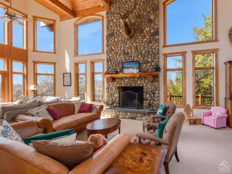 Great Room: Sunlit space with stunning views, stone fireplace, and plush seating for relaxation!Exterior Retreat: Discover stunning views and inviting decks perfect for your Windham getaway!